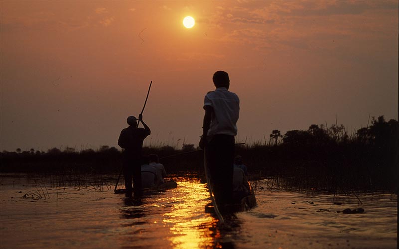 Okavango Origins - people in canoes in the Okavango delta at sunset